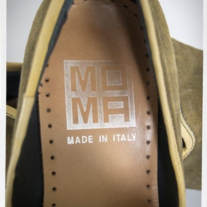Puede incluir: Primer plano del interior de un zapato de ante marr&oacute;n con forro de cuero beige. El zapato tiene una etiqueta que dice "MOMH MADE IN ITALY".