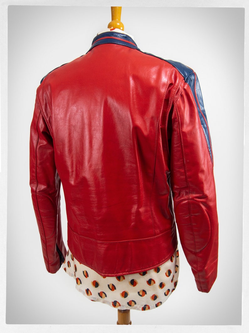 May include: Red leather jacket with blue accents on the collar and sleeves. The jacket has a zipper closure and a stand-up collar.