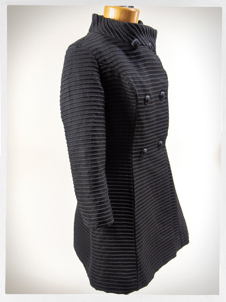 May include: A black, double-breasted coat with a high collar and a ribbed texture.
