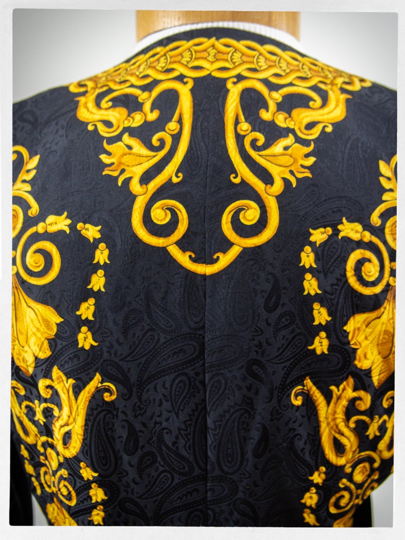 Puede incluir: Blazer negro con un patr&oacute;n de cachemira dorado. El patr&oacute;n presenta intrincados dise&ntilde;os florales y remolinos.