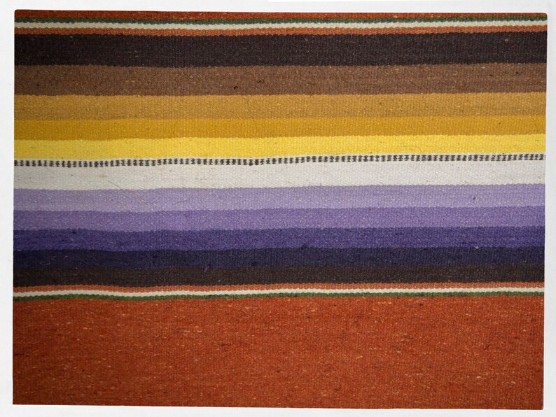 May include: A colorful woven rug with stripes of brown, yellow, purple, and red. The rug has a traditional design and is made of natural fibers.