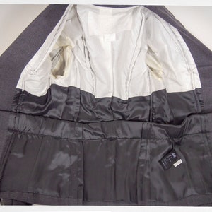 May include: The inside of a gray blazer with a black satin lining. The blazer has a label that reads "H&M Divided".