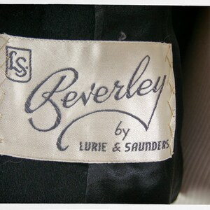 May include: A white label with black text that reads "Beverley by Lurie & Saunders". The label has a small square with the letters "LS" in the top left corner.
