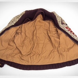 May include: A brown, white, and red patterned knitted cardigan with a zipper closure. The cardigan is unzipped and the inside lining is brown.