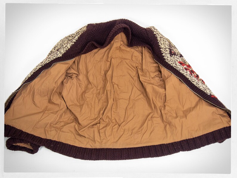 May include: A brown, white, and red patterned knitted cardigan with a zipper closure. The cardigan is unzipped and the inside lining is brown.
