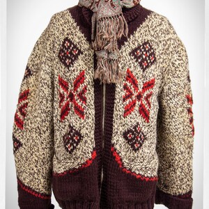May include: A brown knitted cardigan with a zipper closure and a cream and red geometric pattern. The cardigan has two pockets and is worn with a brown paisley scarf.