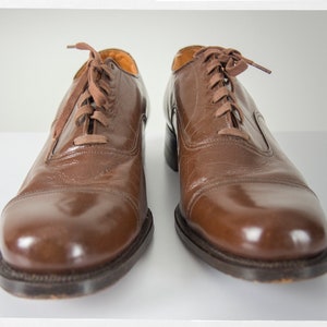 May include: A pair of brown leather lace-up shoes with a polished finish.