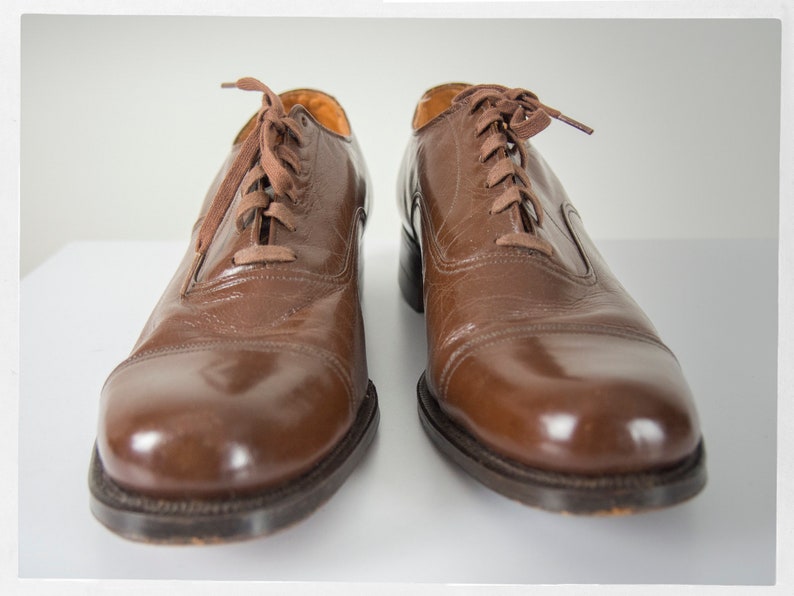May include: A pair of brown leather lace-up shoes with a polished finish.
