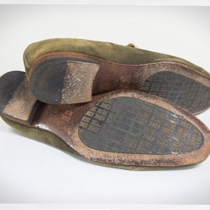 Puede incluir: Un par de zapatos de cuero verde de ante con suela de cuero marr&oacute;n. Las suelas tienen un dise&ntilde;o estampado.