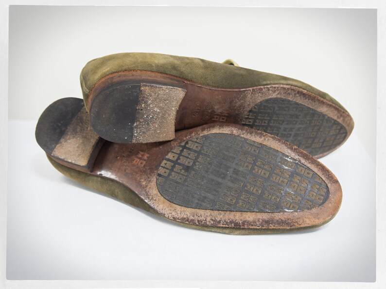 Puede incluir: Un par de zapatos de cuero verde de ante con suela de cuero marr&oacute;n. Las suelas tienen un dise&ntilde;o estampado.