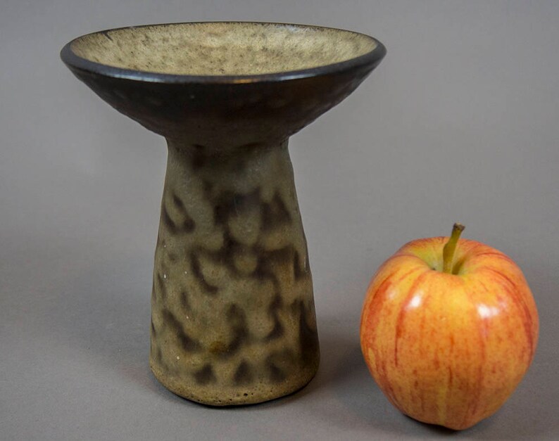 Peut inclure: Un petit vase en c&eacute;ramique brun et beige avec un sommet large et peu profond et une base haute et &eacute;troite. Le vase a une surface marbr&eacute;e et textur&eacute;e.
