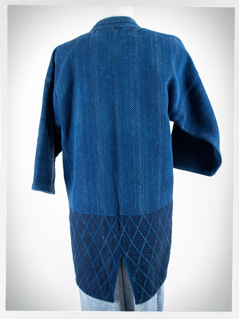 May include: A blue denim jacket with a quilted back panel. The jacket has a relaxed fit and a long length.