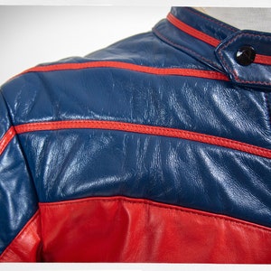 May include: A blue and red leather jacket with red stitching. The jacket has a zipper closure and a stand-up collar.