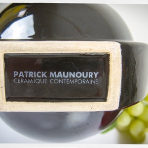 K&ouml;nnte beinhalten: Eine schwarze Keramikvase mit einem wei&szlig;en Etikett, auf dem "Patrick Maunoury, Ceramique Contemporaine" steht.