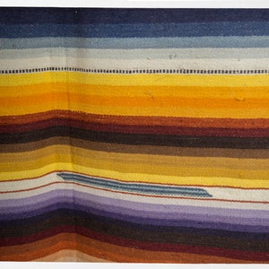 May include: A colorful woven rug with stripes of blue, white, yellow, brown, and purple.