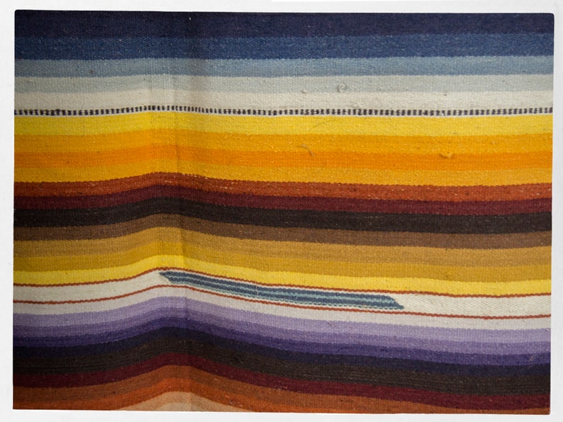 May include: A colorful woven rug with stripes of blue, white, yellow, brown, and purple.