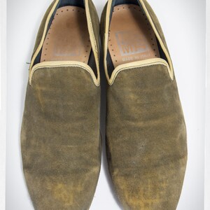 Puede incluir: Un par de zapatillas de ante marr&oacute;n con un ribete marr&oacute;n claro alrededor de la parte superior. Las zapatillas tienen el texto "MADE IN ITALY" en el interior.