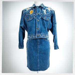 May include: A white ceramic mug with a black handle and the text "But First, Coffee" in a black, handwritten-style font. The mug is on a white surface.