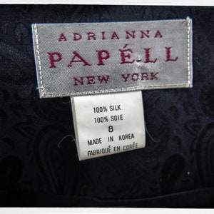 Puede incluir: Un vestido de seda negro con estampado paisley. El vestido tiene una etiqueta que dice "Adrianna Papell New York" y una etiqueta de cuidado que dice "100% Seda, 100% Soie, Hecho en Corea, Fabriqu&eacute; en Cor&eacute;e".