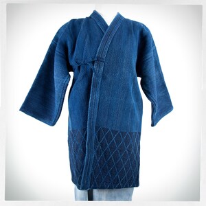 May include: A blue indigo cotton Japanese-style jacket with a diamond pattern on the bottom. The jacket has a tie closure at the front.