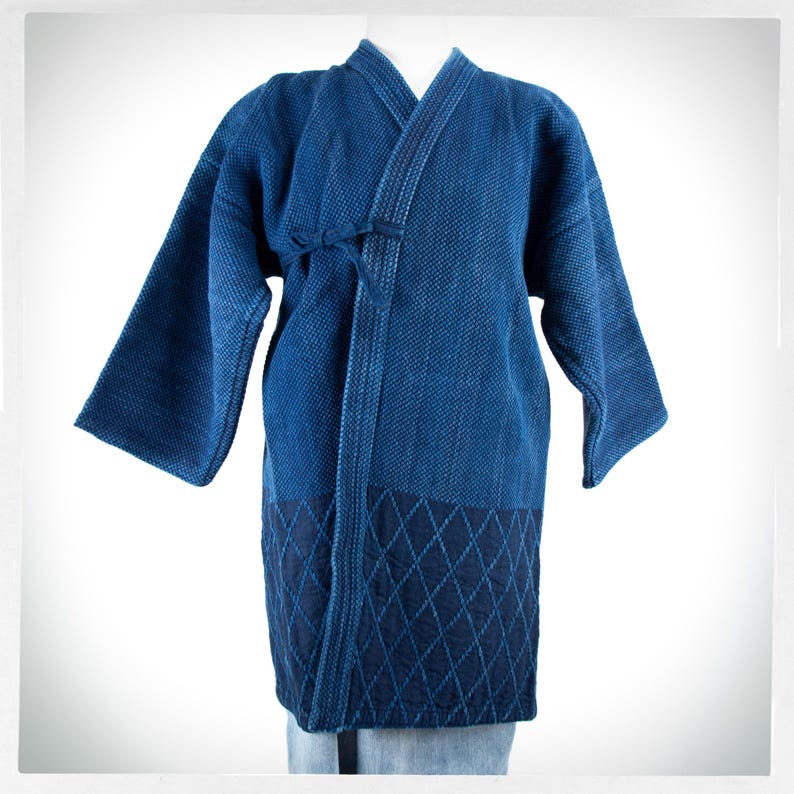May include: A blue indigo cotton Japanese-style jacket with a diamond pattern on the bottom. The jacket has a tie closure at the front.