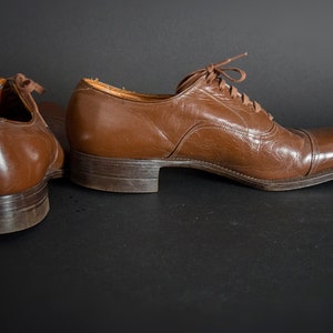 May include: A pair of brown leather lace-up shoes. The shoes have a classic design and are in good condition.