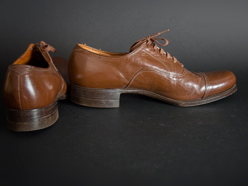 May include: A pair of brown leather lace-up shoes. The shoes have a classic design and are in good condition.