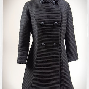 May include: A black double-breasted coat with a high collar and a ribbed texture.