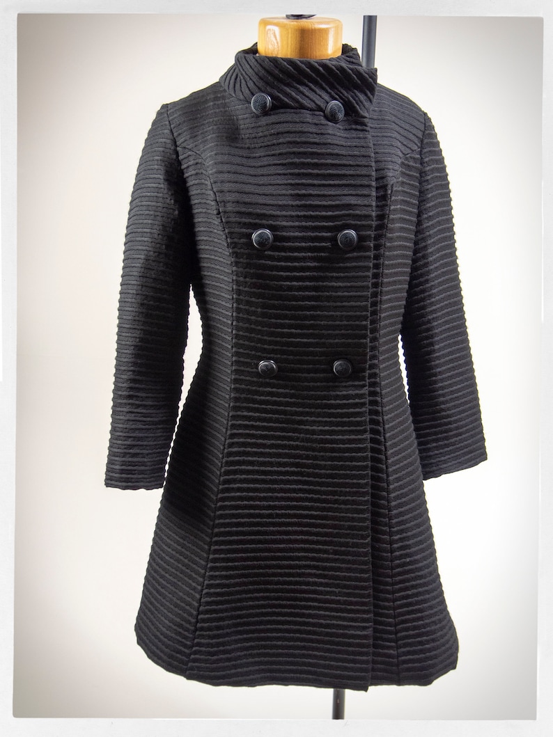 May include: A black double-breasted coat with a high collar and a ribbed texture.