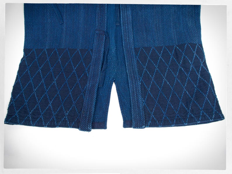 May include: A blue indigo cotton kimono with a diamond pattern on the bottom hem.