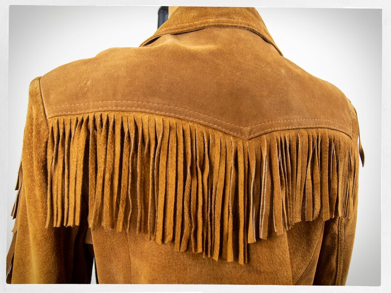 May include: Brown suede jacket with fringe detail on the back and sleeves.