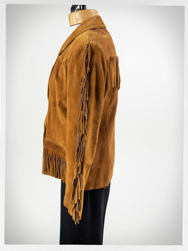 May include: A brown suede jacket with fringe detailing on the sleeves and hem.