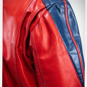 May include: Red leather jacket with blue leather panels and white stitching. The jacket has a sporty look.