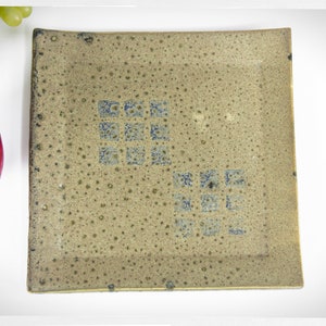 May include: A square ceramic plate with a speckled brown glaze and a blue geometric pattern.