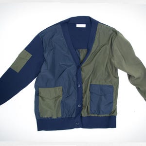 May include: A blue, green, and navy blue cardigan with a v-neck and two pockets. The cardigan is made of a patchwork of different fabrics.