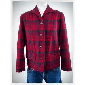 May include: A red and black plaid wool jacket with a collared neckline and button closure. The jacket has two pockets and is shown on a mannequin.