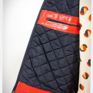 May include: Red leather jacket with a black quilted lining and a zipper closure. The jacket has a zippered pocket on the inside.