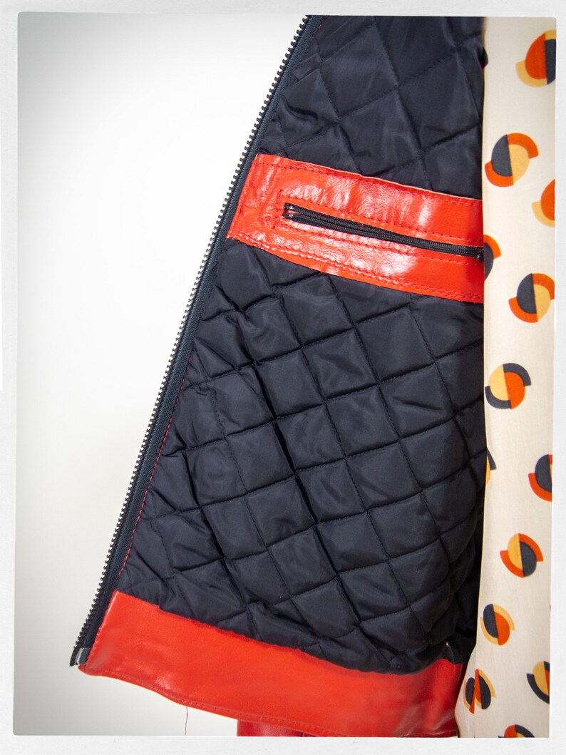 May include: Red leather jacket with a black quilted lining and a zipper closure. The jacket has a zippered pocket on the inside.