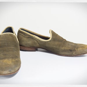 Puede incluir: Un par de mocasines de ante marr&oacute;n con un ribete marr&oacute;n claro alrededor de la parte superior. Los mocasines tienen una punta puntiaguda y un tac&oacute;n bajo.