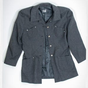 May include: A dark gray blazer with a collared neckline, button closure, and two front pockets. The blazer has long sleeves and a tailored fit. The brand name "Copac" is visible on the label.