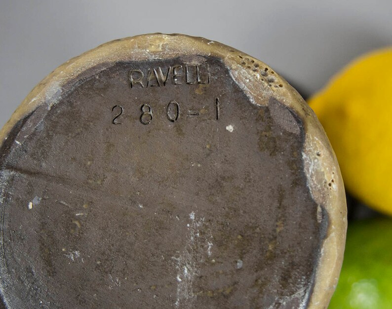 Peut inclure: Le fond d'un vase en c&eacute;ramique brun avec le texte "RAVELLO 280-1" estampill&eacute; au fond.