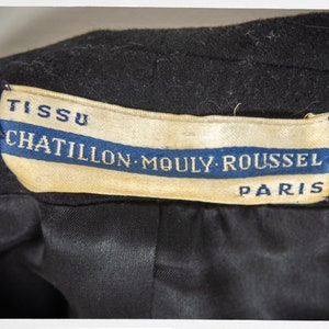 May include: A black fabric label with white text that reads "TISSU CHATILLON-MOULY-ROUSSEL PARIS". The label has a blue stripe with white text.