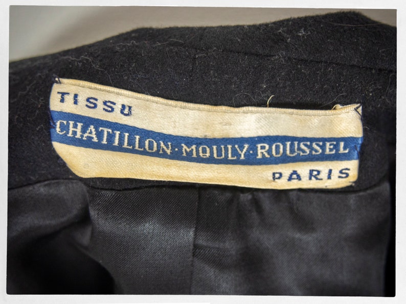 May include: A black fabric label with white text that reads "TISSU CHATILLON-MOULY-ROUSSEL PARIS". The label has a blue stripe with white text.
