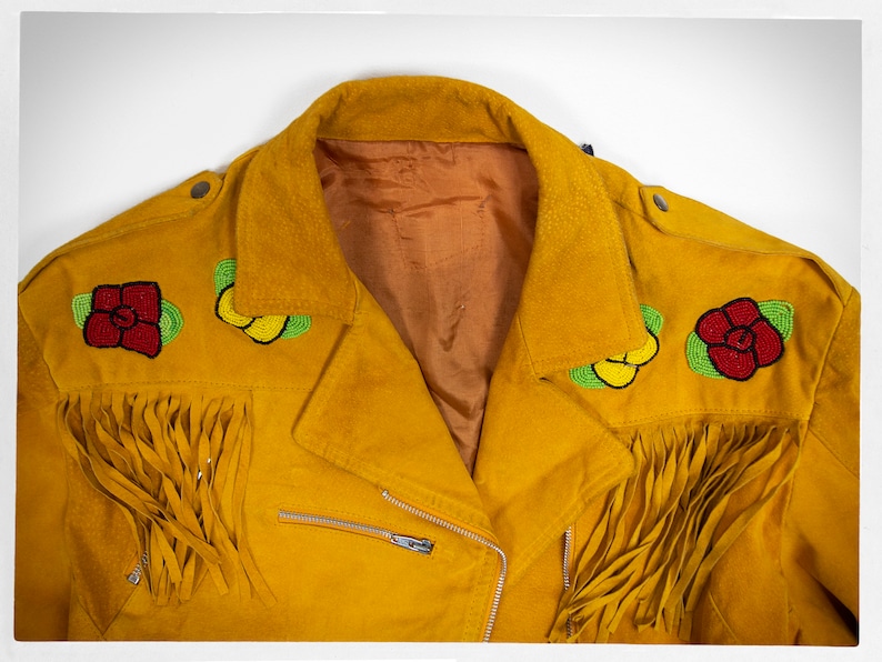 May include: A yellow suede jacket with beaded floral embellishments and fringe detailing. The jacket has a zipper closure and a brown lining.