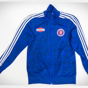 May include: A blue Adidas track jacket with white stripes down the sleeves and a Detroit City logo on the chest. The jacket has a blue and black floral pattern.