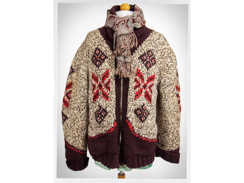 May include: A brown knitted cardigan with a cream and red geometric pattern. The cardigan has a zipper closure and a scarf with a paisley pattern.
