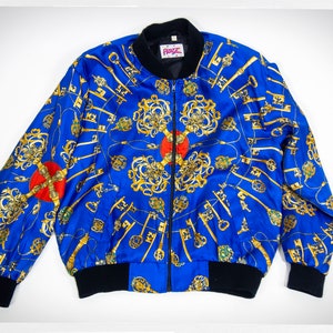 May include: A blue satin bomber jacket with a black zipper and black ribbed cuffs and waistband. The jacket features a gold and red key pattern.
