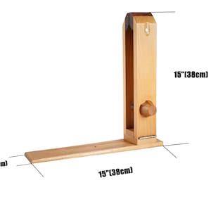 May include: A wooden leathercraft stitching pony, 38cm long and 8cm wide. The tool is made of light-coloured wood and features a vertical clamp and a horizontal base. A wooden knob is visible on the side.