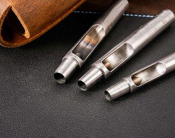 May include: Three silver leather hole punches of different sizes on a black leather surface.
