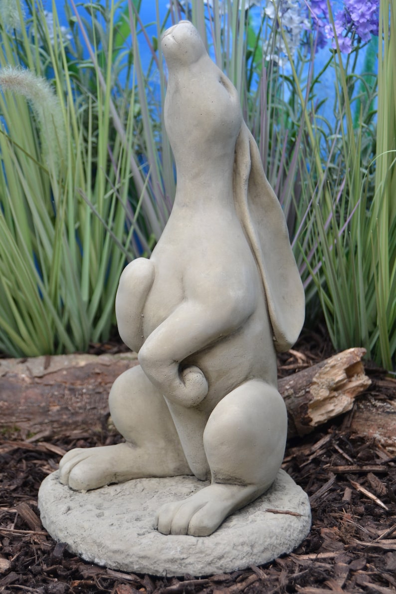 Pu&ograve; includere: Una scultura in cemento grigio di un coniglio in piedi sulle zampe posteriori con la testa inclinata verso l'alto. Il coniglio sta guardando il cielo. La scultura &egrave; seduta su una base rotonda.